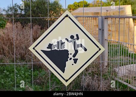 Sign attached to metal fence at Fort Manoel in Malta warning of the dangers of falling. Stock Photo