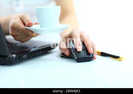 Close-up of businesswoman's hand on mouse and cup of coffee Stock Photo