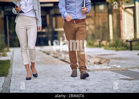 cropped image of male and female businesspeople walking through arranged park Stock Photo