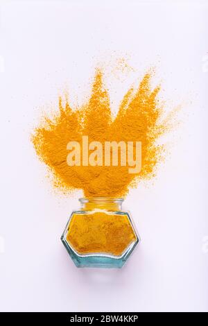 from the glass bowl a sprinkling of turmeric on a white background. seen from above Stock Photo