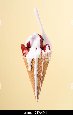 in the waffle cone, whole strawberries covered with a dripping white yogurt cream Stock Photo