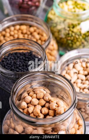 variety of dried legumes in glass jars. selective focus on the jar in the foreground with chickpeas Stock Photo