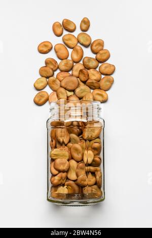 glass vase with dried broad beans in the foreground, top view and isolated from the white background Stock Photo