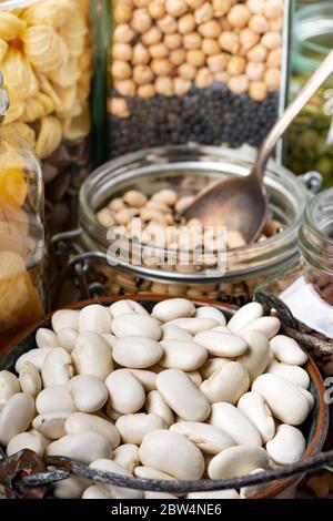 variety of dried legumes and Italian pasta in glass jars in the foreground Stock Photo