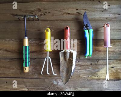 Modern farming tool hang on an old wooden wall in a barn. Close up Stock Photo