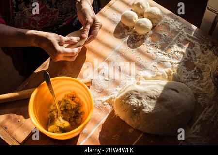 Senior woman prepares pies on a table in her home kitchen Stock Photo