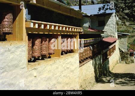 Buddhist prayer cylinders containing mantras, holy words, on Tibetan monastery in a village amid the Himalayas, Nepal. Stock Photo