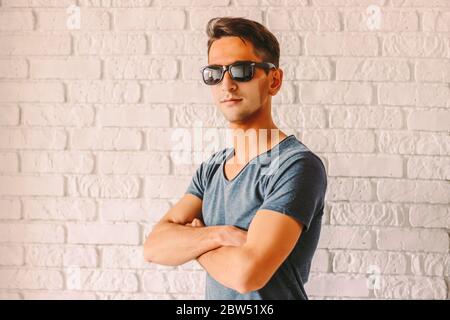 Portrait of stylish man in sunglasses with funny tan lines from medical face mask. Young happy hipster man with red sunburn skin after wearing protect Stock Photo