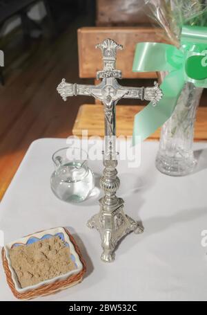 Crucified Christ in old silver crucifix next to other accessories for the Eucharist on a table. Stock Photo