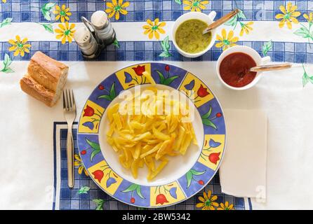 Potato chips dish next to two sauces on a table. Stock Photo