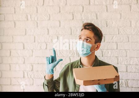 https://l450v.alamy.com/450v/2bw53jd/happy-hipster-guy-courier-in-medical-face-mask-and-rubber-gloves-hold-cardboard-pizza-box-in-hand-look-up-point-to-copy-space-man-delivery-service-2bw53jd.jpg