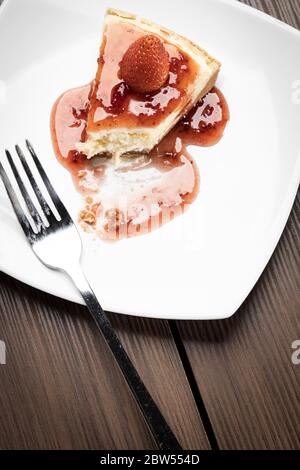 delicious slice of  strawberries cheesecake on a white plate on a wooden table Stock Photo