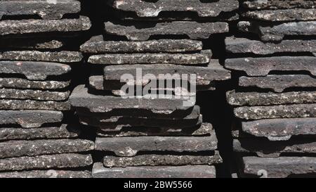 A close up of worn concrete roof tiles stacked into piles Stock Photo
