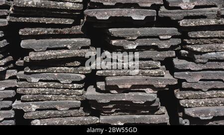 Worn concrete roof tiles stacked into piles Stock Photo