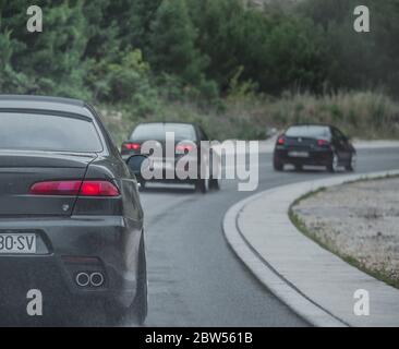 Multiple Alfa Romeos driving in a column. Enthusiasts owners meeting and driving to festival on a cold rainy day. Modified Alfa Romeo 156 in focus Stock Photo