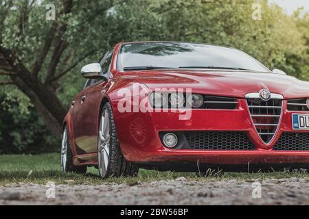 Beautiful red Alfa Romeo 159s shining on soft afternoon sun. Parked in nature as a part of an italian car enthusiast meet up Stock Photo