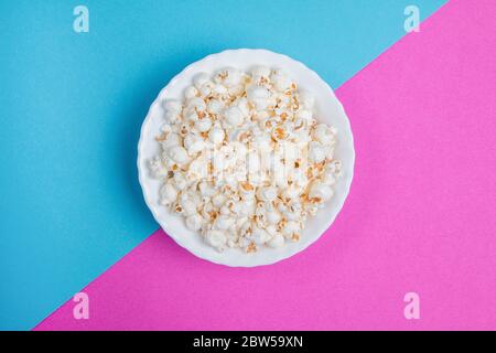 White bowl of popcorn on a blue and purple background Stock Photo