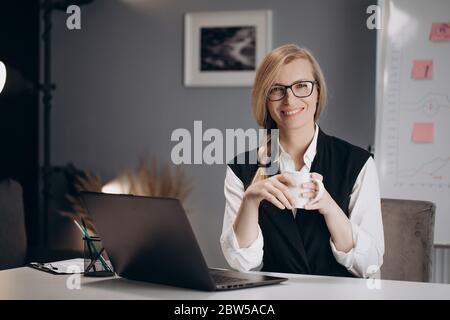 Business lady drinking coffee while working on laptop Stock Photo