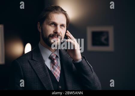 Handsome bearded man in business suit talking on smartphone Stock Photo