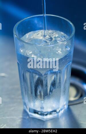 Glass filling with tap water in a sink. Stock Photo