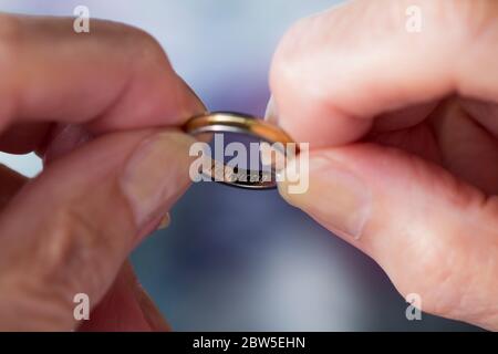 Close-up of hands holding a wedding ring inscribed with a name. Stock Photo