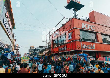 A KFC Kentucky Fried Chicken restaurant on the corner of a packed inner city street on a Sunday evening in Pondicherry, India Stock Photo