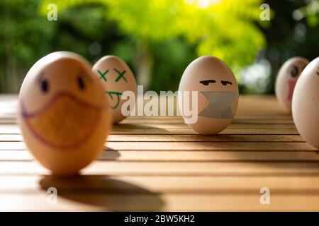 Funny eggs with human faces. Eggs wearing face masks or chinstraps. Selective focus. Colored chinstraps on white eggs. Stock Photo