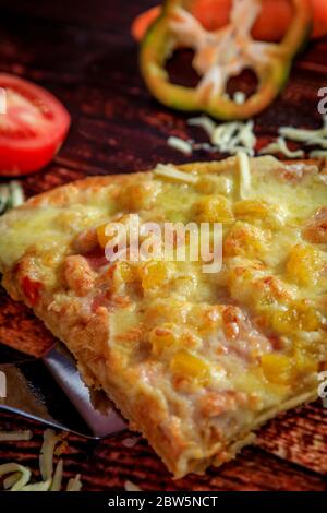 Hawaiian homemade pizza slice with ham and pineapple and mozzarella cheese on traditional wooden background table Stock Photo