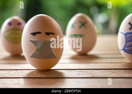 Eggs with drawings of faces with chinstraps. Concept of protection and social distancing. Eggs on a table. Contagious disease concept. Stock Photo