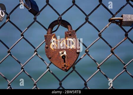 Padlocks on Barbed Wire Fence at Oceanfront in San Francisco, California, with View of Water Stock Photo