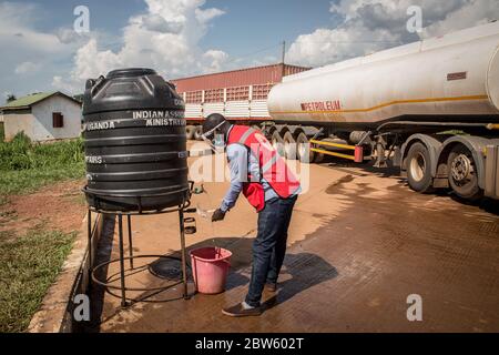 Elegu, Uganda. 28th May, 2020. A medic washes his hands in front of a temperature checkpoint at the Elegu border point between Uganda and South Sudan.Uganda closed its borders in March to everyone except cargo planes and truck drivers. Credit: SOPA Images Limited/Alamy Live News Stock Photo