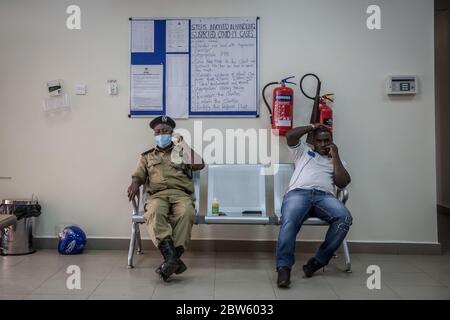 Elegu, Uganda. 28th May, 2020. Officials sit in front of a sign listing the steps involved in handling suspected COVID-19 cases, at the Elegu border point between South Sudan and Uganda.Uganda closed its borders in March to everyone except cargo planes and truck drivers. Credit: SOPA Images Limited/Alamy Live News Stock Photo