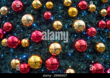 Red and gold ball decorations on a Christmas tree with lights on. Stock Photo