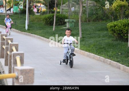Hotan, China's Xinjiang Uygur Autonomous Region. 28th May, 2020. Children ride bikes at the Yuquan Lake Park in Hotan City, northwest China's Xinjiang Uygur Autonomous Region, May 28, 2020. Located to the south of the Taklimakan Desert, Hotan City has taken on a new look as the living environment is improved a lot with the modernization of infrastructure. Credit: Sadat/Xinhua/Alamy Live News Stock Photo