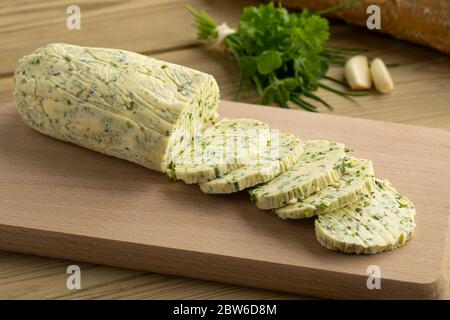 Sliced fresh made herb butter close up on a cutting board Stock Photo