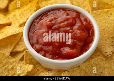 Bowl of red spicy mexican salsa surrounded by tortilla chips Stock Photo
