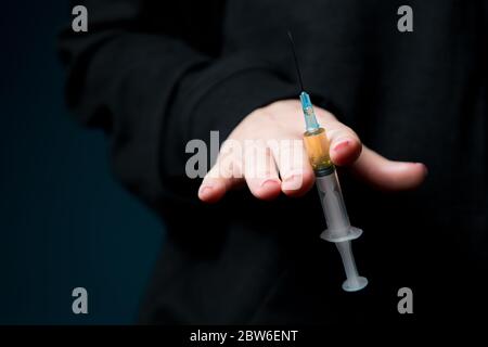 female hand holds a syringe filled into the camera, close up, no face Stock Photo