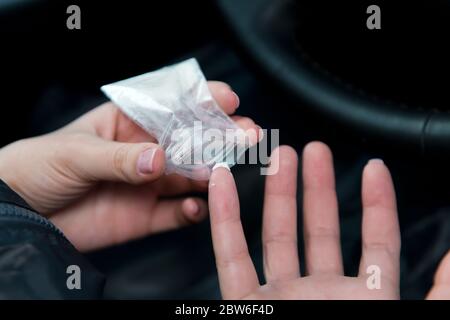 girl takes a dose of cocaine from the package with a fingernail Stock Photo