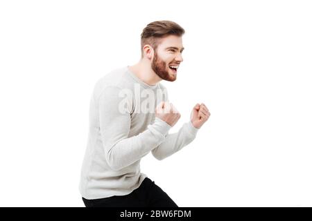 Young man celebrating the win with yes gesture. Guy celebrating the win or rooting for success over white background Stock Photo