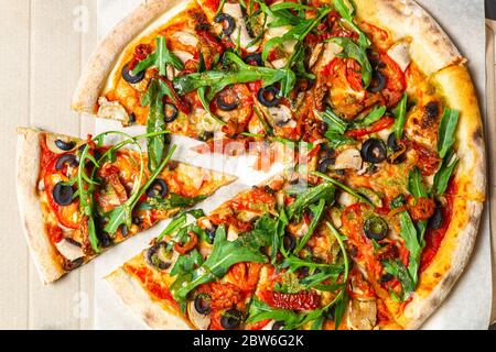 Delicious Italian top view.Fast food delivered in cardboard box.Tasty natural ingredients baked in oven on thin crusty dough base.Black olives,arugula Stock Photo