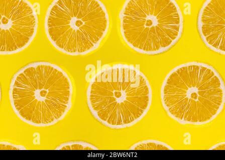 Pattern of fresh sliced lemon on yellow background. Lemons fruits. Juicy slice of lemon on yellow background Stock Photo