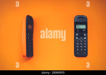 Two wireless cordless telephone, radiotelephone, dect cordless phone wireless phone, radiotelephone, radio phone on orange background Stock Photo