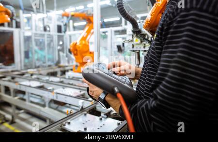 Engineer setting up automatic robot arms in the smart factory, automotive industry, industrial concept Stock Photo