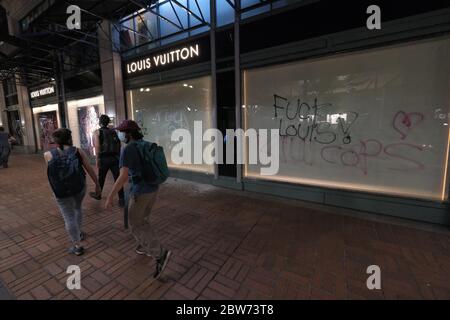 Portland, USA. 29th May, 2020. Protesters walk by graffiti on the Louis  Vuitton store in Portland, Ore., on May 29, 2020. (Photo by Alex Milan  Tracy/Sipa USA) Credit: Sipa USA/Alamy Live News