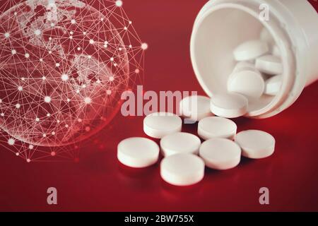 Pills spilling out of pill bottle with virtual hologram earth on a red background. Medicine, pharmacy and healthcare Stock Photo