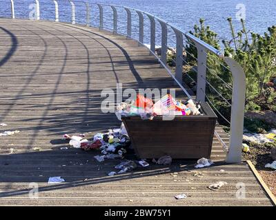 Overflowing trash can on the waterfront in the recreation area. Garbage bin. Pile of plastic garbage waste on the floor. Stock Photo