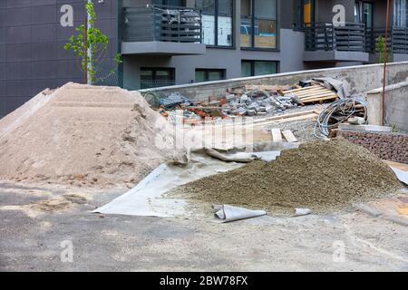 A construction site with a pile of sifted sand and cement in the background of a new residential building in the open. Stock Photo