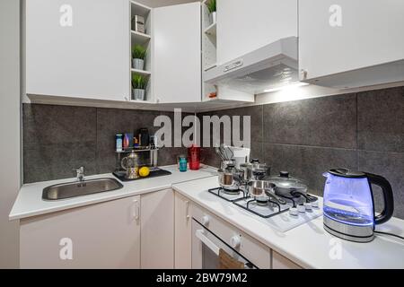 White kitchen set in modern loft interior of kitchen in apartment. Faucet and sink. Oven. Metal pans. Stock Photo