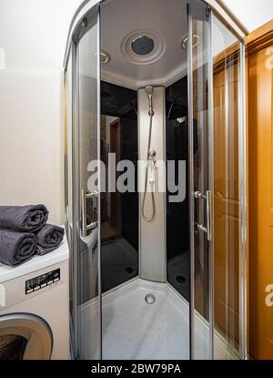 Modern interior of bathroom in apartment. Shower cabin. Rolled grey towels on the washing machine. Stock Photo