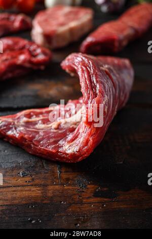 Bio Flank bavette or flap steak beef t steak near tri-tip and top blade oyster cuts close up in front of other cuts in butchery on old wood table side Stock Photo